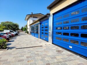Porta rapida ad impacchettamento con finestrature in PVC installata su un capannone artigianale